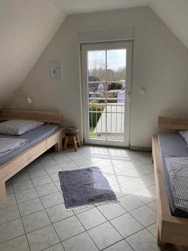 a bedroom with two beds and a sliding glass door at Ferienhaus Steilküste in Fehmarn