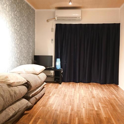 a living room with a black curtain and a desk at Guest House Fukuoka W305 in Kasugabaru