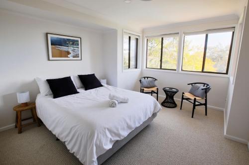 a bedroom with a large white bed with two chairs at Bayview Oasis- With pool in Hardys Bay