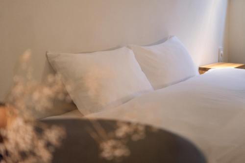 a bed with white sheets and pillows on it at Design Hotel Kyoto Fuyacho in Kyoto