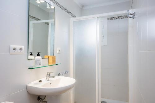 een witte badkamer met een wastafel en een douche bij Apartamento mhm 2 in Cala Ratjada
