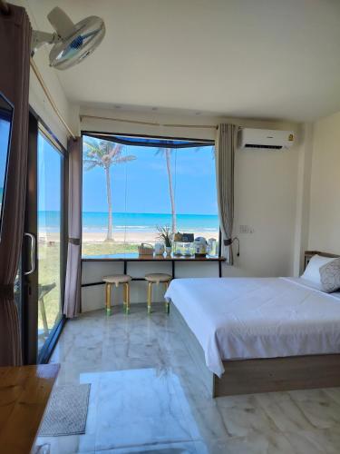 a bedroom with a bed and a view of the beach at Baan Be Beach in Lang Suan