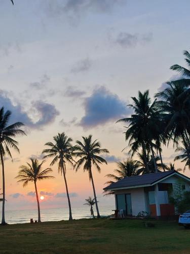 a house with palm trees in front of the ocean at Baan Be Beach in Lang Suan