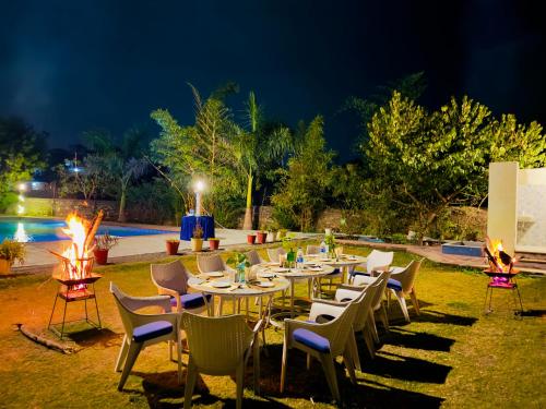 een groep tafels en stoelen in een tuin 's nachts bij Jag Aravali Resort Udaipur- Experience Nature away from city Hustle in Udaipur