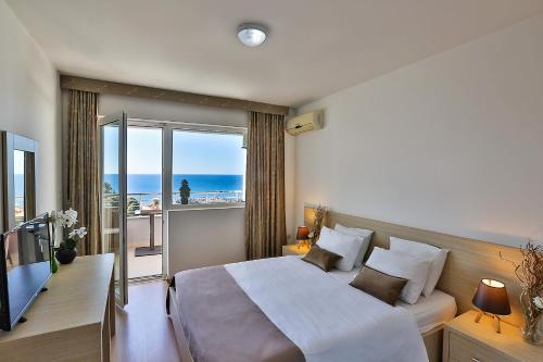a bedroom with a bed and a balcony with the ocean at Kolomat in Sveti Stefan