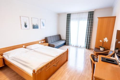 um quarto com uma cama e um sofá em Leonfeldner-Hof em Bad Leonfelden