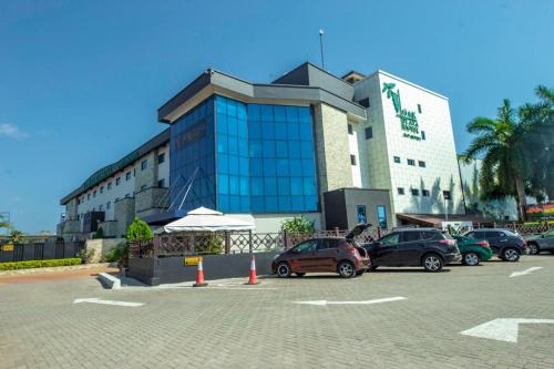 a parking lot with cars parked in front of a building at Oak Plaza Hotels East Airport in Accra