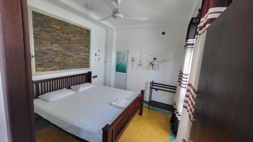 a small bedroom with a bed and a brick wall at BB GUESTHOUSE in Ambalangoda
