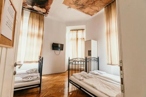 a bedroom with two beds and two windows at Hostel Franz Ferdinand in Sarajevo