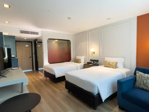 a hotel room with two beds and a blue couch at A-ONE Bangkok Hotel in Bangkok