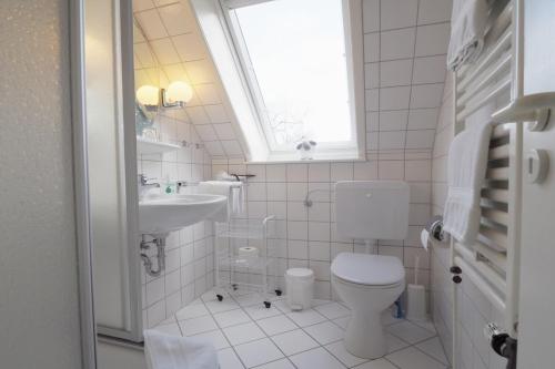 baño con aseo y lavabo y ventana en Ferienwohnung Helgoländer Straße, en Wyk auf Föhr