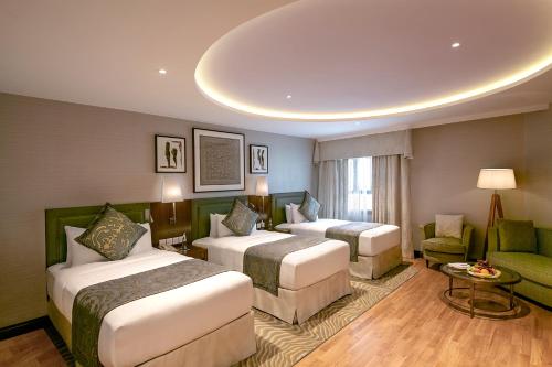 a hotel room with two beds and a couch at The Oberoi Madina المدينة أوبروي in Al Madinah