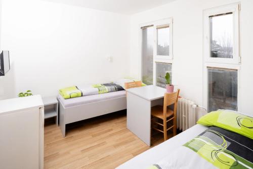 a white room with a bed and a desk and window at Penzion a ubytovna Oáza in Otrokovice