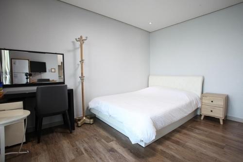 a bedroom with a bed and a desk with a computer at Poem House in Jeju