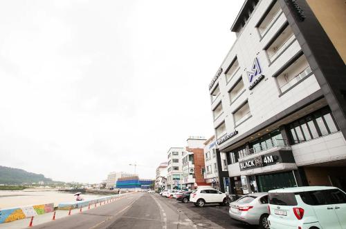 a street with cars parked in front of a building at Poem House in Jeju