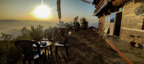 a group of tables and chairs on a patio with the sunset at Dadaghare Homestay & View Point Restaurant in Panauti