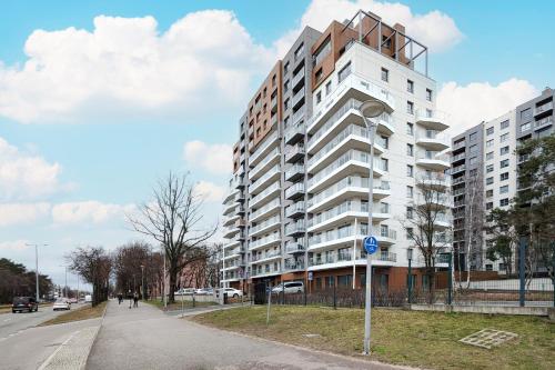 a tall white building on the side of a street at 9th Floor Green and Grey Apartment in Gdańsk Brzeźno with Two Bedrooms and Parking by Renters in Gdańsk