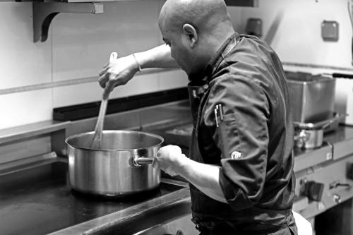 a man stirring a pot in a kitchen at Negrecoste Hôtel & Spa in Aix-en-Provence