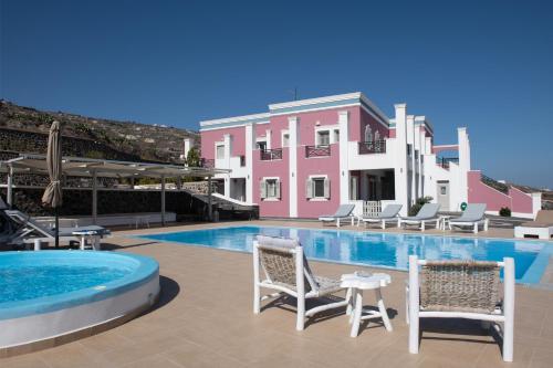 a swimming pool with chairs and a pink building at Rose Suites in Vourvoúlos