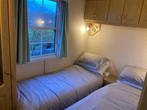 Duas camas num pequeno quarto com uma janela em Bridge Farm Caravan em Buxton