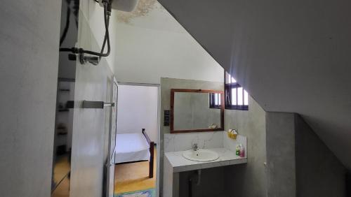 a bathroom with a sink and a mirror and a bed at BB GUESTHOUSE in Ambalangoda