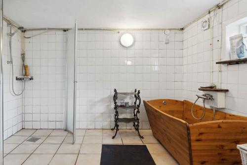 a bathroom with a wooden tub and white tiles at Bokrsvej 10, 9340 Asaa in Aså