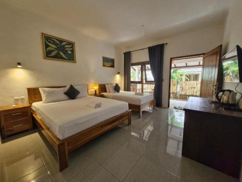 a hotel room with two beds and a television at Bale Kebon Rangsot in Pawenang