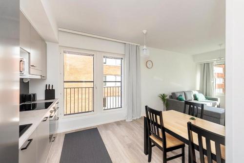 a kitchen and a living room with a table and a dining room at Kotimaailma Apartments Oulu in Oulu