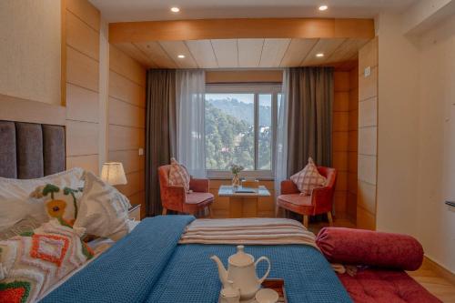 a bedroom with a bed and chairs and a window at Super Hotel by Perfectstayz Mall Road in Mussoorie