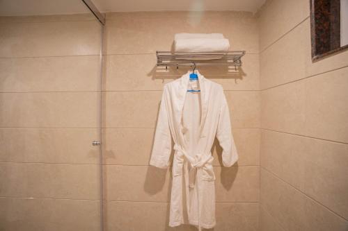 a white robe is hanging on a rack in a bathroom at Super Hotel by Perfectstayz Mall Road in Mussoorie