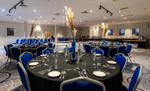 a banquet hall with tables and blue chairs at Copthorne Aberdeen Hotel in Aberdeen