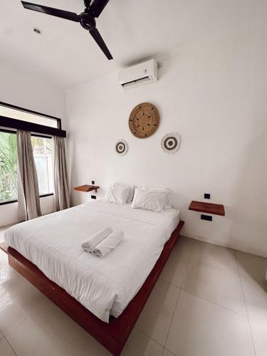a bedroom with a bed with white sheets and a ceiling fan at Susurro Residential in Kuta Lombok