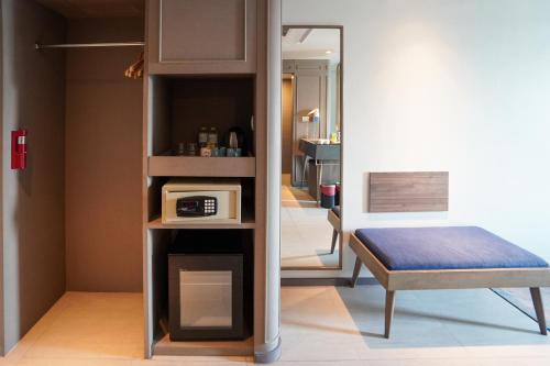 a small room with a bed and a microwave at Tinidee Trendy Bangkok Khaosan in Bangkok