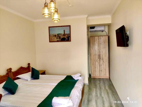 a hotel room with two beds and a television at Antique Hotel Rizvan in Bukhara