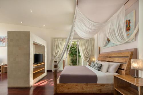 een slaapkamer met een groot bed en een televisie bij The Seiryu Boutique Bali Villas in Seminyak