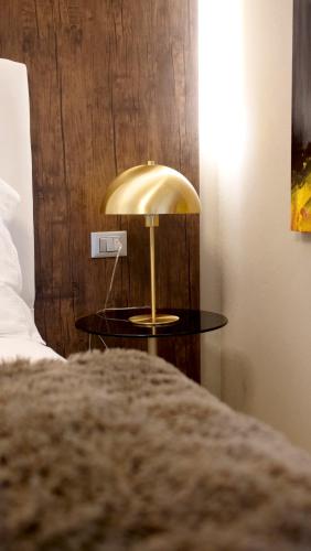 a gold lamp on a table next to a bed at Hotel Battisti 31 in Brescia