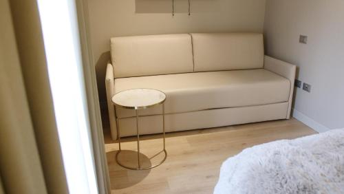 a white couch in a small room with a table at Hotel Battisti 31 in Brescia