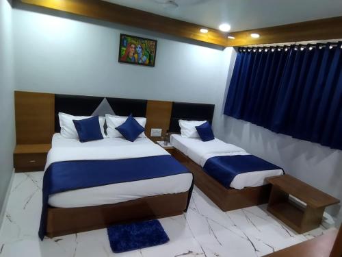 a bedroom with two beds with blue and white pillows at HOTEL SHREE RADHE in Ahmedabad