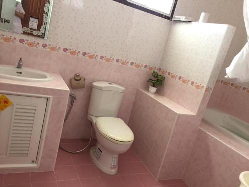 Baño de color rosa con aseo y lavamanos en Wan Ton vacation home, en Nakhon Sawan