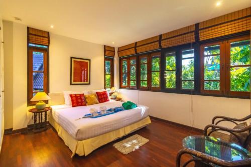 a bedroom with a bed in a room with windows at Kamala Beach Estate Resort - SHA Extra Plus in Kamala Beach