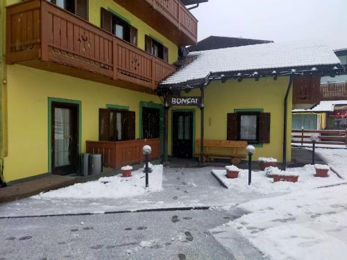 a yellow building with snow in front of it at Garnì Bonsai in Pinzolo