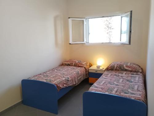 two beds in a small room with a window at Casa Alba by My Home Apulia in Torre Lapillo