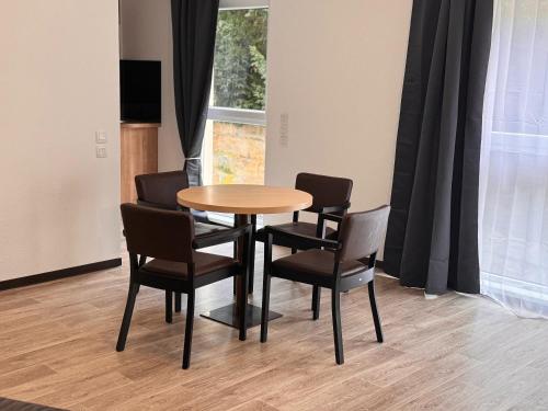 - une table et des chaises dans une chambre avec fenêtre dans l'établissement KOSY Appart'Hôtel 7ème Art, à Saint-Avold