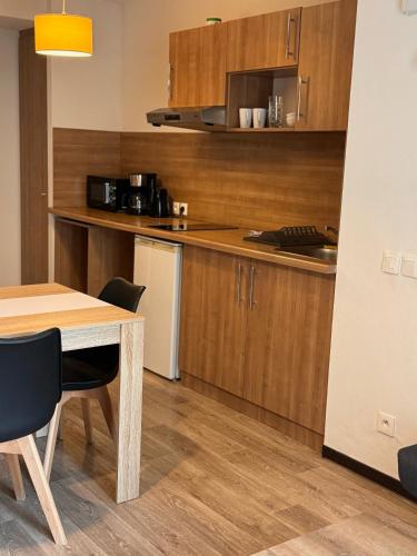 une cuisine avec des armoires en bois et une table et des chaises dans l'établissement KOSY Appart'Hôtel 7ème Art, à Saint-Avold