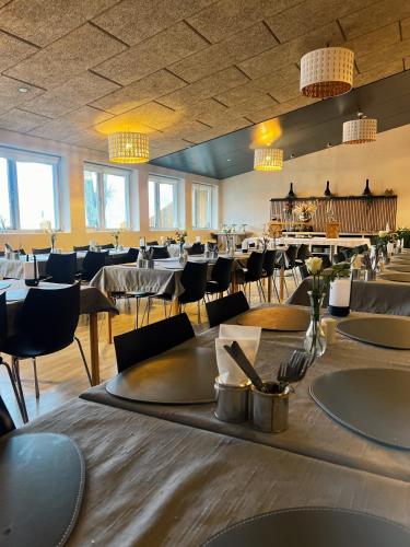a dining room with tables and chairs and lights at KonceptHotel in Oksbøl