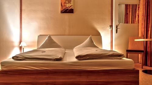 a bed with two pillows on top of it at Parkhotel Kirchberg in Kirchberg in Tirol