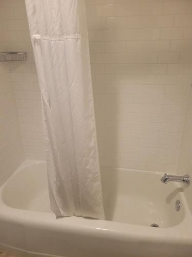 a white bath tub with a shower curtain on it at Natural Bridge Hotel, Trademark Collection by Wyndham in Natural Bridge