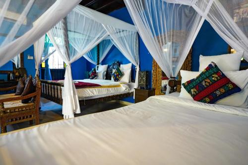 1 dormitorio con 2 camas con cortinas blancas en Jafferji House en Zanzíbar