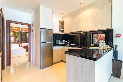 a kitchen with a refrigerator and a counter top at Kamala Beach Estate Resort - SHA Extra Plus in Kamala Beach