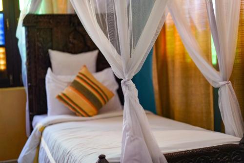 a bedroom with a canopy bed with white sheets and pillows at Jafferji House in Zanzibar City